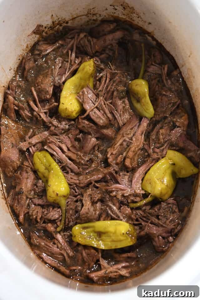 Homemade Mississippi Pot Roast 5 Shredded beef in a slow cooker, bathed in rich gravy with scattered pepperoncini.