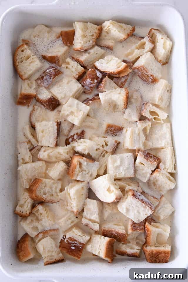 White pan with bread and egg and milk mixture.