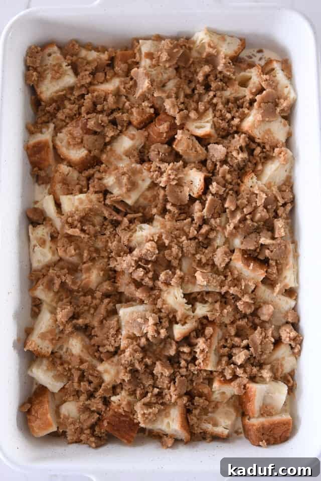 White pan with bread cubes, milk and egg mixture and cinnamon streusel.