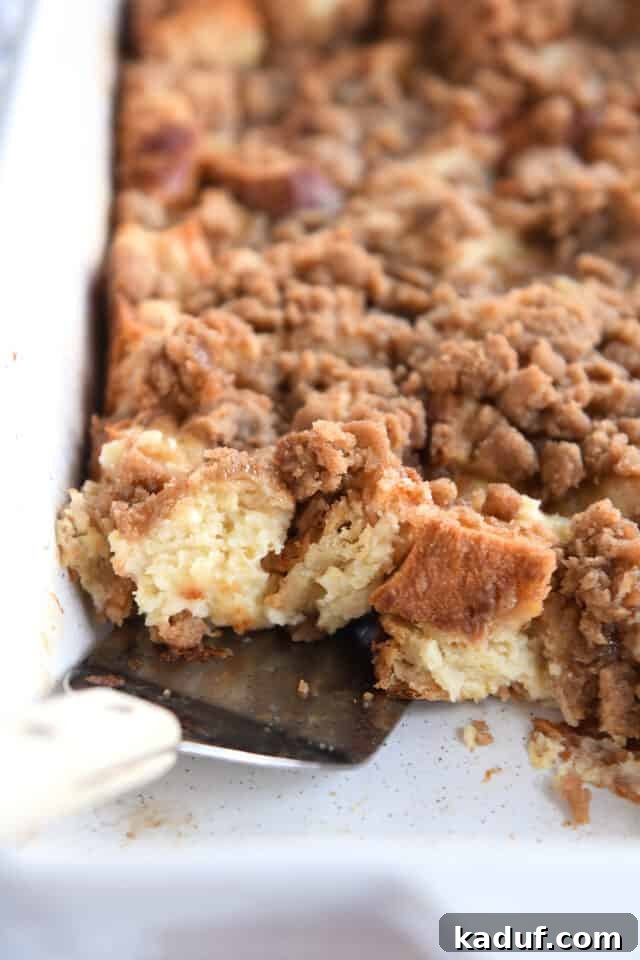 Spatula scooping up French toast bake in white pan.