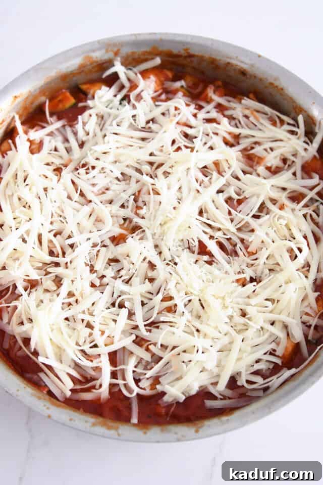 One-Pan Italian Cheesy Chicken and Zucchini 6 Mozzarella cheese on top of tomato sauce in stainless skillet.