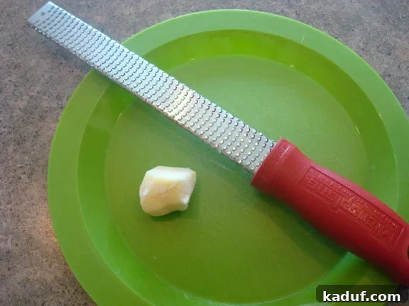 How to Effortlessly Grate Fresh Ginger 2 a microplane and a chunk of fresh ginger on a green plate