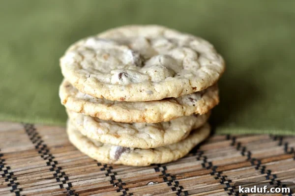 Toasted Hazelnut Chocolate Chip Cookies 3 A beautifully arranged stack of freshly baked chocolate chip hazelnut cookies resting on a textured mat and a vibrant green napkin, ready to be enjoyed.