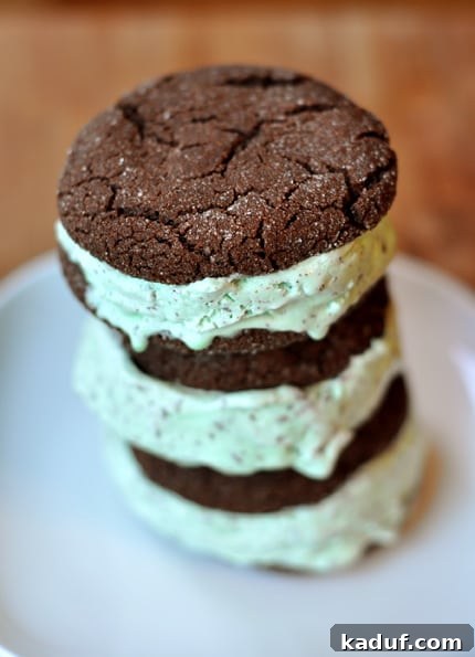 Frozen Mint Chocolate Chip Delights 2 A stack of three homemade chocolate mint chip ice cream sandwiches on a white plate, showcasing the rich chocolate cookies and vibrant green mint ice cream filling.