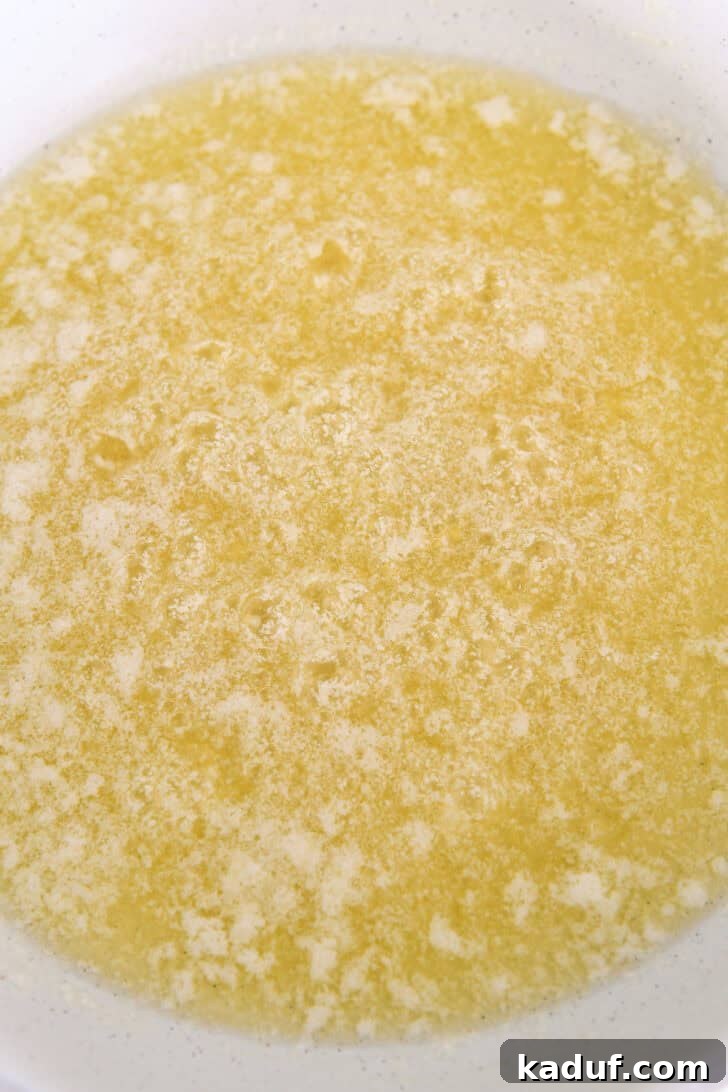 Butter beginning to foam and melt in a light-colored skillet, a crucial step in browning butter.