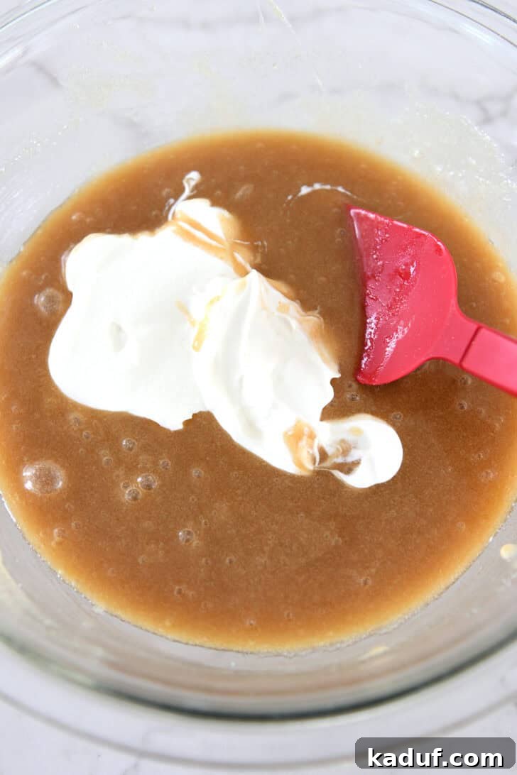 Creamy sour cream is added to the developing muffin batter, enhancing moisture and tenderness.