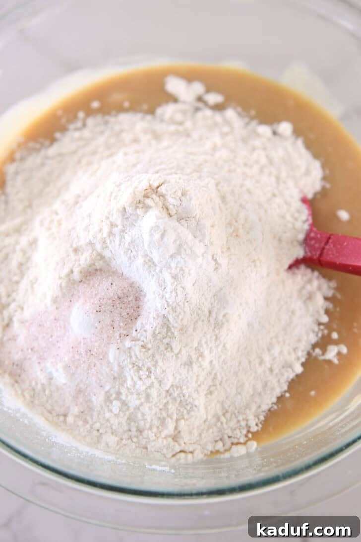 Dry ingredients, including flour, baking powder, and salt, are gently added to the wet muffin batter.