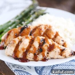 Sticky coconut chicken on white plate with coconut rice and asparagus