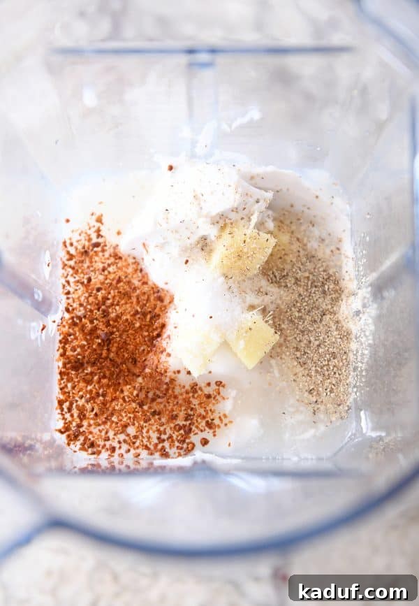 Caramel Coconut Chicken 6 A top-down view of a blender filled with a creamy white marinade mixture, containing visible chunks of fresh ginger and other spices, ready to be blended for the sticky coconut chicken.