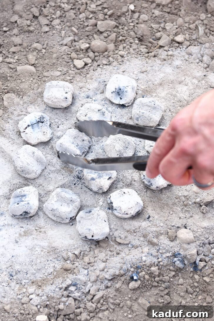 Hearty Dutch Oven Lasagna 13 Placing hot coals in dirt for Dutch oven cooking, creating a stable base.
