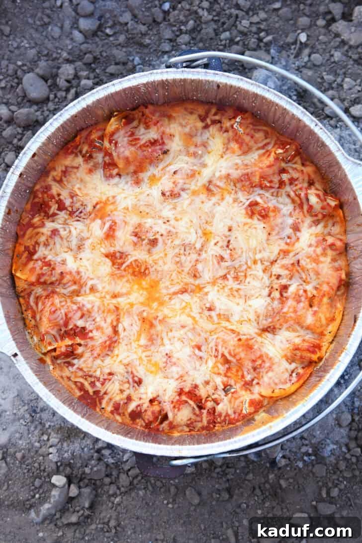 Hearty Dutch Oven Lasagna 16 Top down view of cooked lasagna in Dutch oven with liner, bubbling and golden.