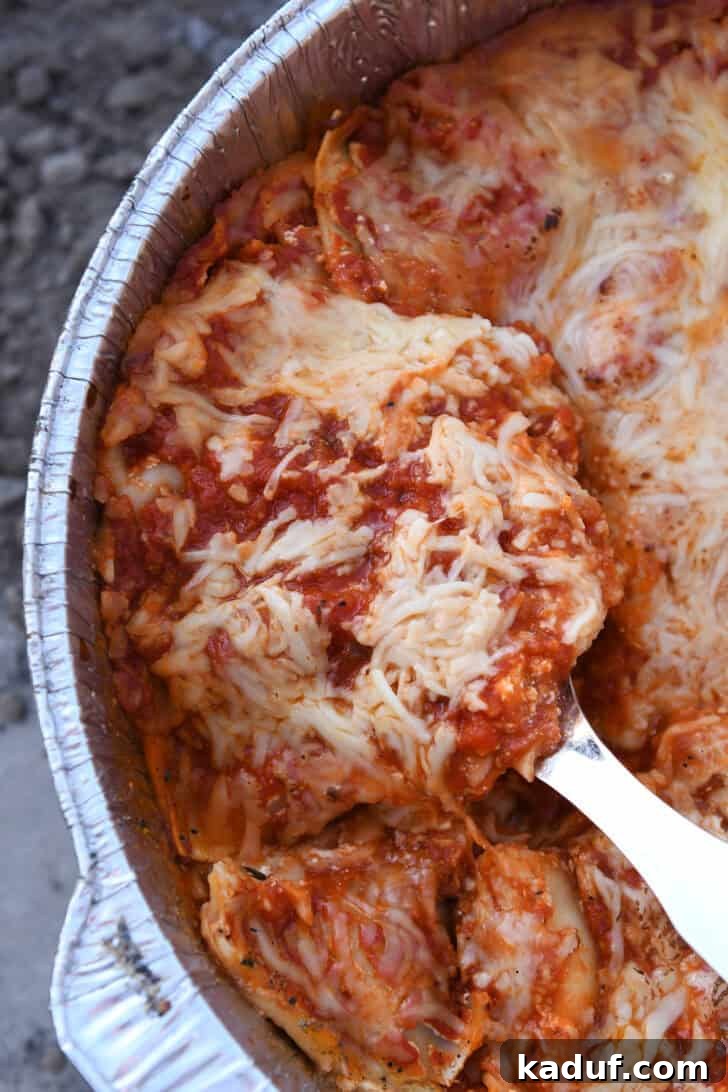 Hearty Dutch Oven Lasagna 17 Serving spoon scooping generous portion of Dutch oven lasagna, showing layers.