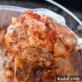Scooping serving of Dutch oven lasagna with serving spoon.