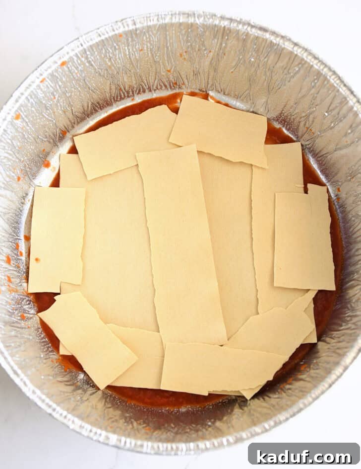 Hearty Dutch Oven Lasagna 6 Top down view of broken lasagna noodles layered in Dutch oven liner.
