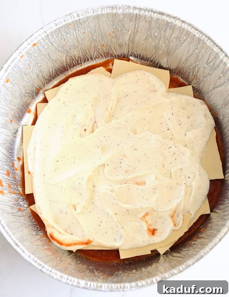 Hearty Dutch Oven Lasagna 7 Top down view of creamy cottage cheese mixture over noodles in Dutch oven liner.