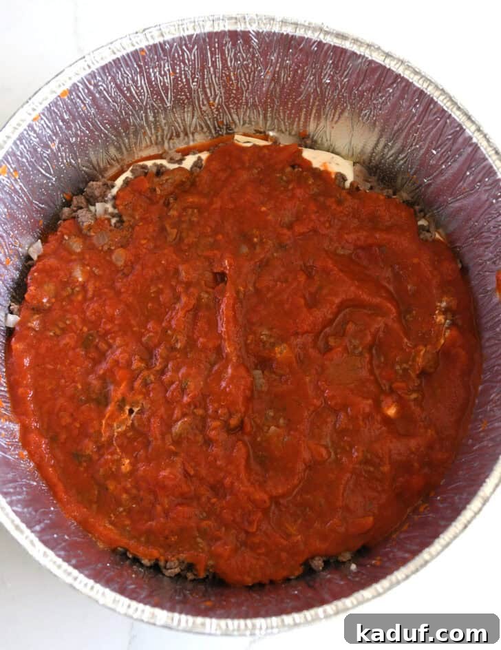 Hearty Dutch Oven Lasagna 9 Top down view of pasta sauce layered in Dutch oven liner.