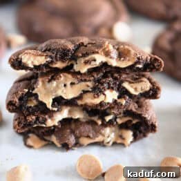Four chocolate peanut butter chip cookies, broken in half and stacked, showcasing their gooey, melted centers.
