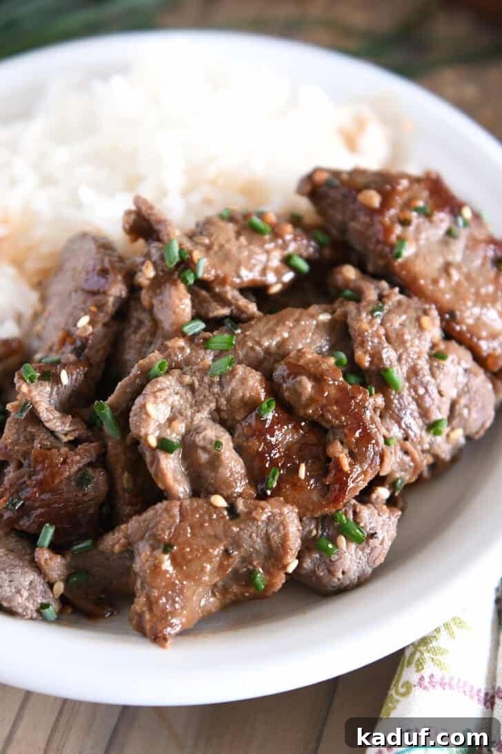 Simple Korean Beef Bulgogi 7 White plate with white rice and several pieces of Korean beef bulgogi, green onions and sesame seeds.