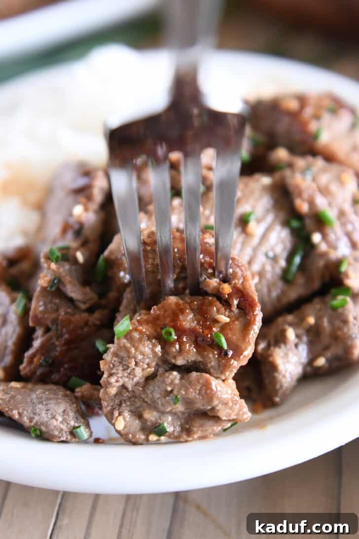 Simple Korean Beef Bulgogi 8 Fork piercing piece of cooked beef bulgogi.