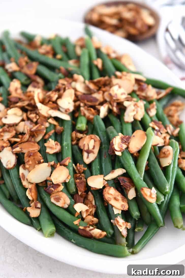 Simple Green Beans Almondine 7 White tray with beautifully steamed green beans, toasted almonds, and aromatic garlic and shallots.