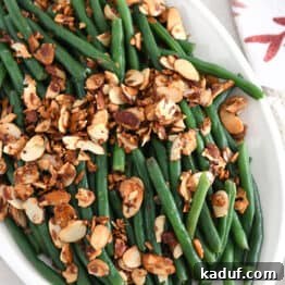 Top down view of steamed green beans with toasted almonds, garlic and shallots.