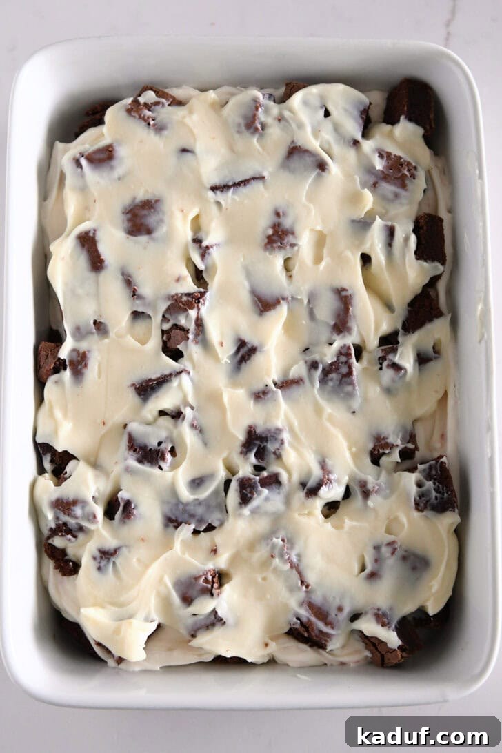 Mint Chocolate Brownie Trifle 11 Second pudding layer spread over the top of brownie cubes in a white baking dish.