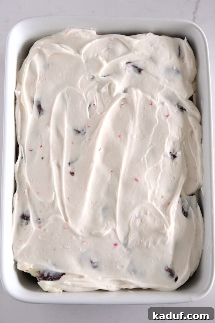 Mint Chocolate Brownie Trifle 12 Second peppermint cream cheese layer spread over the top of pudding in a white baking dish.