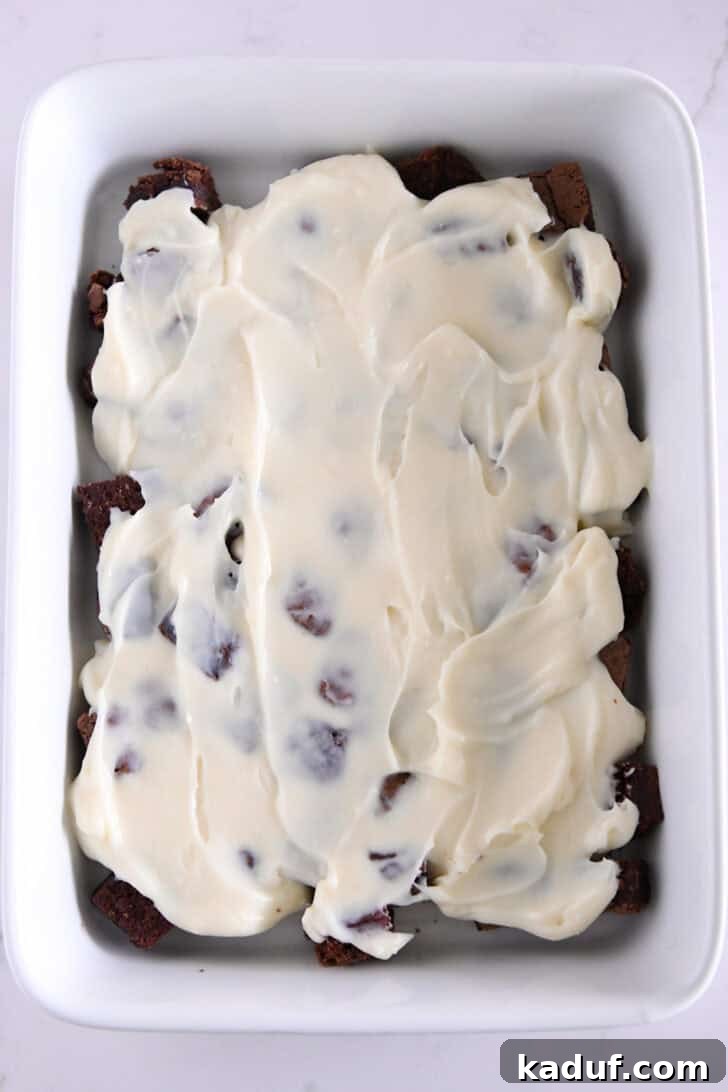 Mint Chocolate Brownie Trifle 8 White chocolate pudding layer spread over brownie cubes in a white baking dish.