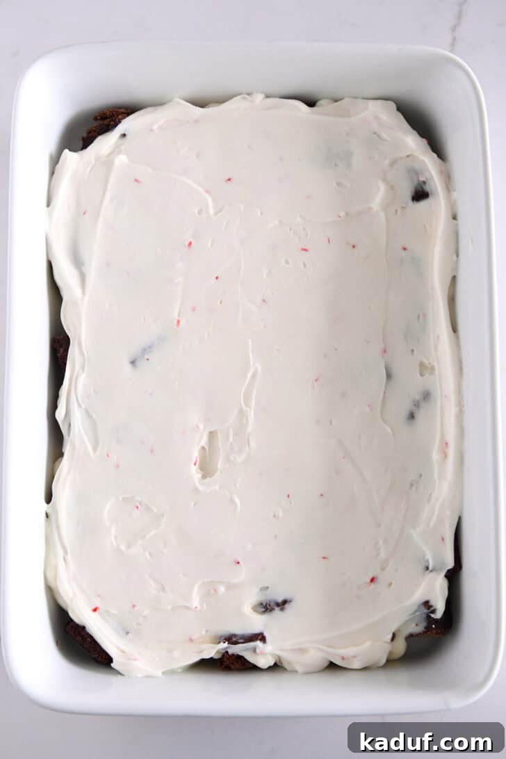 Mint Chocolate Brownie Trifle 9 Peppermint cream cheese layer spread over pudding and brownies in a white dish.
