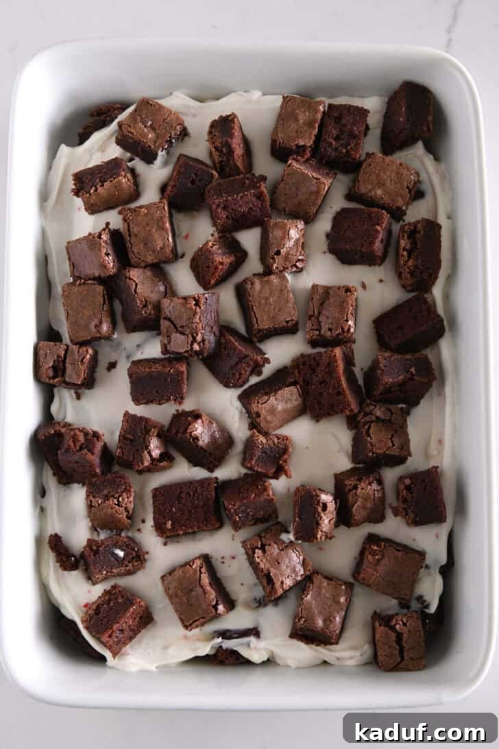 Mint Chocolate Brownie Trifle 10 Second layer of brownie cubes on top of peppermint cream cheese layer in a white dish.