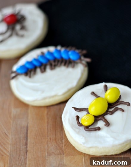 Monster Munchies Wrapped and Crawling 4 Sugar cookies with white frosting topped with various chocolate-shaped bugs with M&M accents.