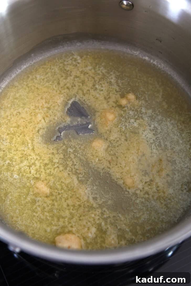 Fragrant Garlic Butter Rice 3 Butter and garlic simmering in a stainless steel pot, releasing a fragrant aroma.