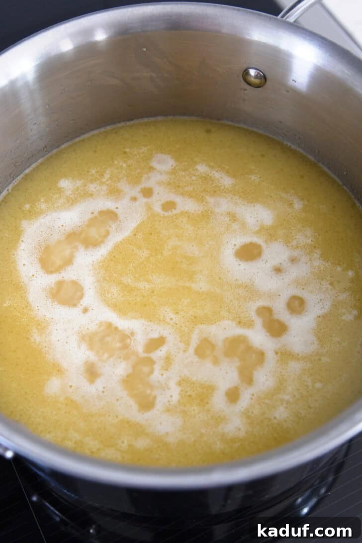 Fragrant Garlic Butter Rice 6 Chicken broth simmering with rice in a stainless steel pot, ready to be covered.