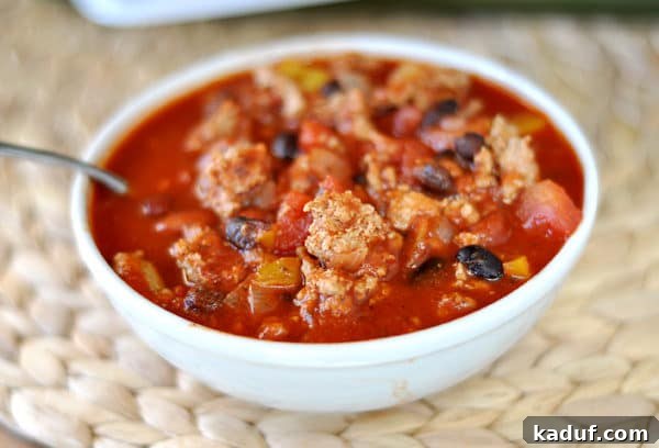 Comforting Turkey and Bean Chili 3 A top-down view of a vibrant white bowl of black bean turkey chili, showcasing the rich texture and colorful ingredients of the hearty meal.