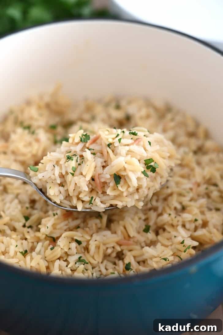 Ultimate Rice Pilaf 7 Serving spoon gracefully lifting fluffy rice pilaf from a cast iron pot.