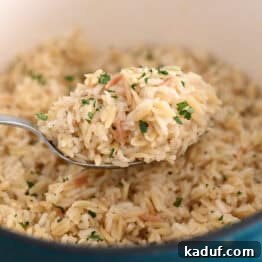 Serving spoon with rice pilaf in a cast iron pot, showcasing its golden color and fluffy texture.