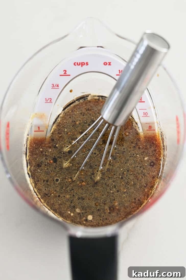Ultimate Baked Salmon 3 Top down view of liquid measuring cup with small whisk, soy sauce, and brown sugar.