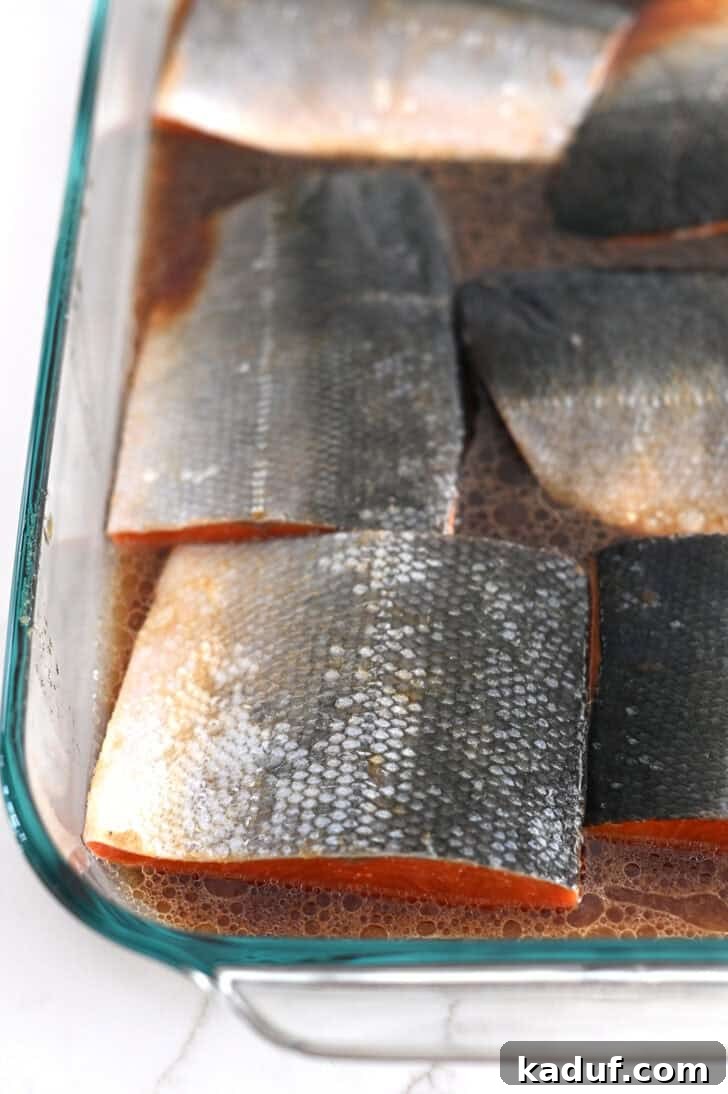 Ultimate Baked Salmon 4 Salmon filets skin side up in glass pan with brown marinade.