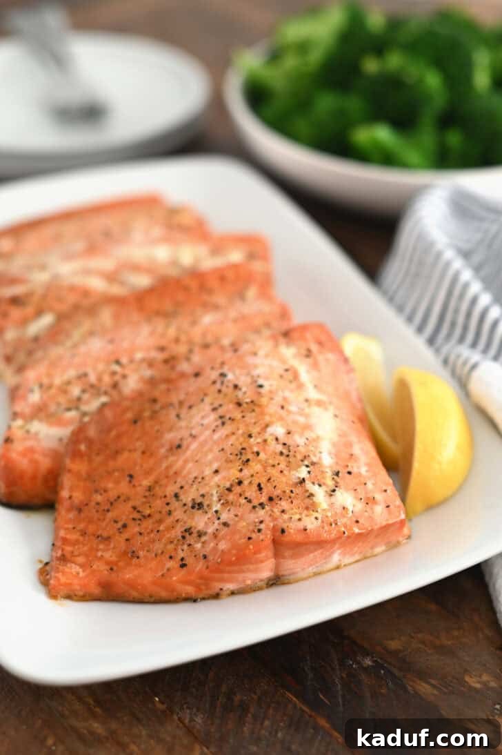 Ultimate Baked Salmon 7 Three baked salmon filets on white platter with lemon slices.