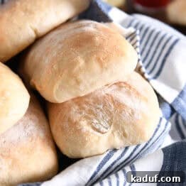 Fresh Ciabatta Rolls Made Today 15 Several baked and flour dusted ciabatta rolls in white dish with blue and white towel.