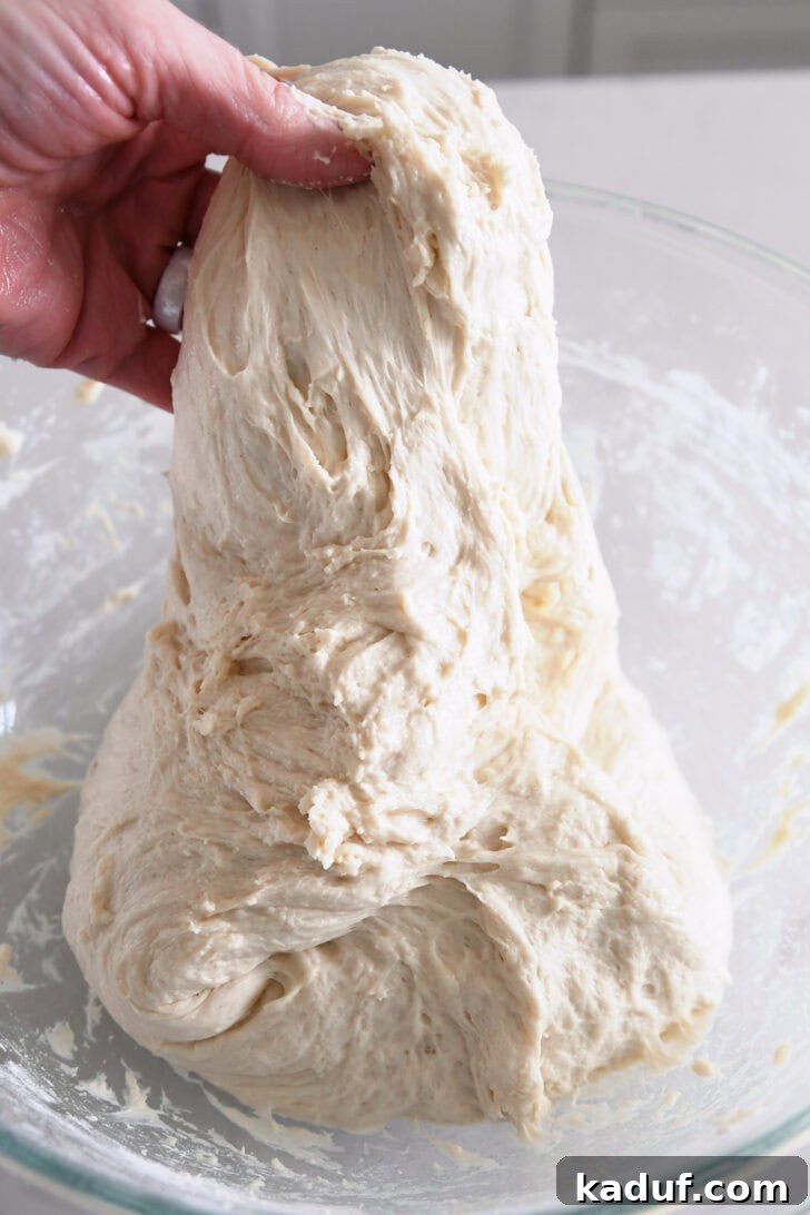 Fresh Ciabatta Rolls Made Today 7 Lifting dough up for stretch and folds in a glass bowl.
