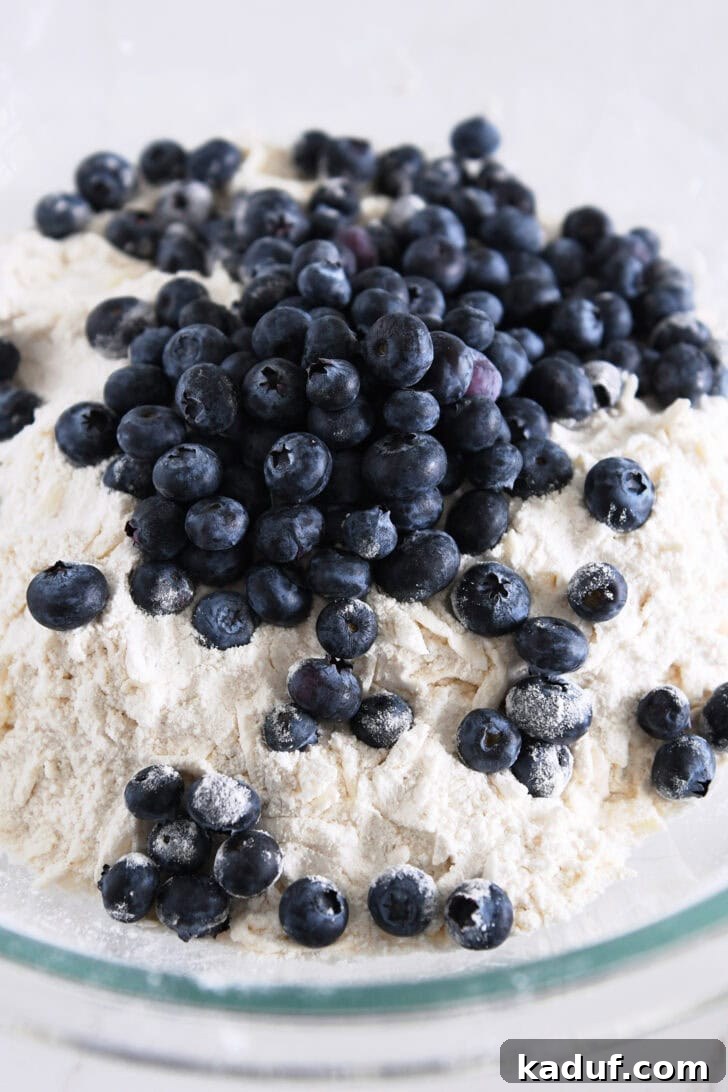 Irresistible Lemon Blueberry Scones 4 Fresh blueberries added to the bowl with butter shreds and dry scone ingredients, ready for mixing.