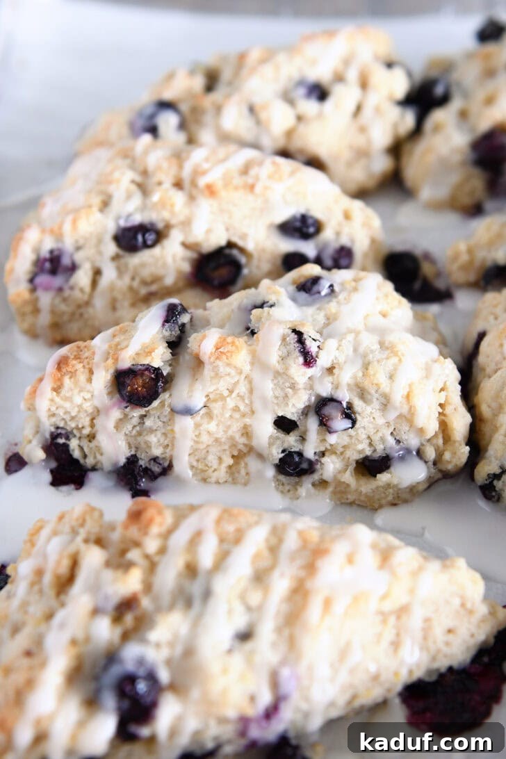 Irresistible Lemon Blueberry Scones 10 Glazed baked lemon blueberry scones arranged on a parchment-lined baking sheet, showcasing their golden crust and glaze.