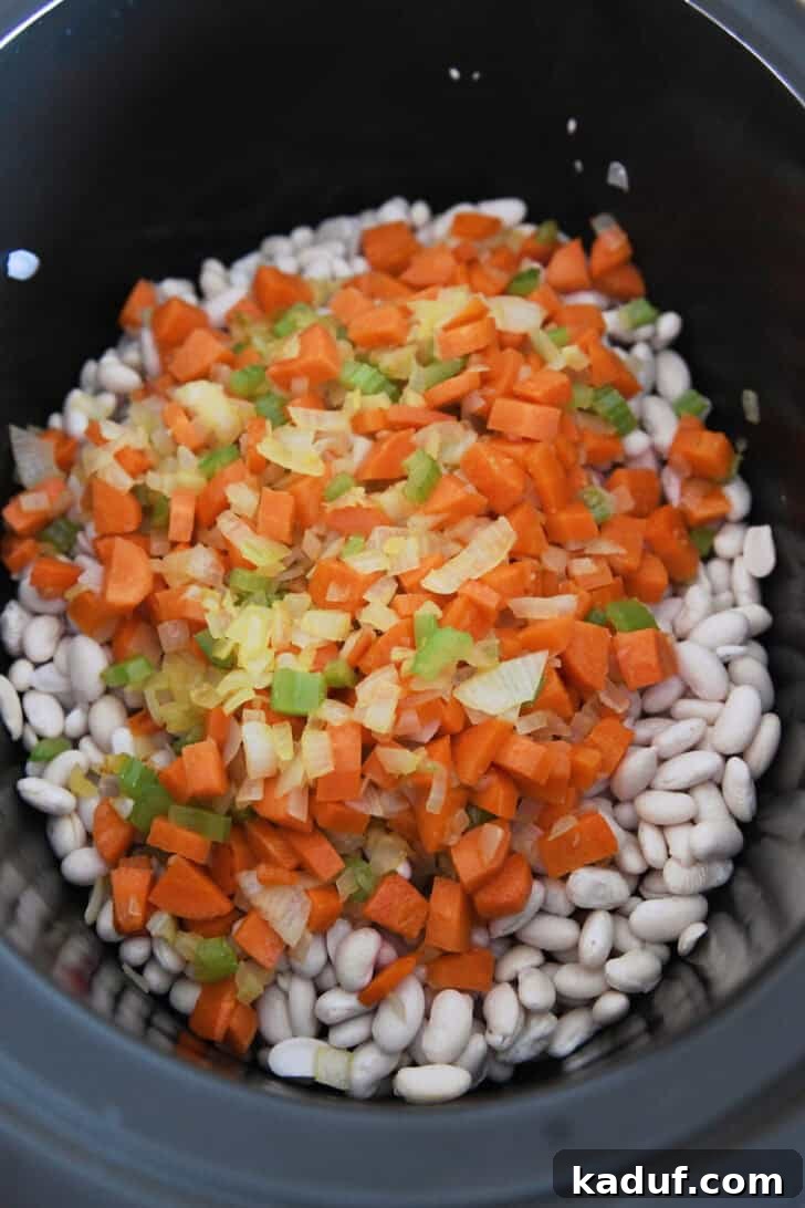 Hearty Slow Cooked Ham and Bean Soup 4 Slow cooker filled with dry white beans, colorful carrots, celery, and onions, ready for the ham bone and broth.