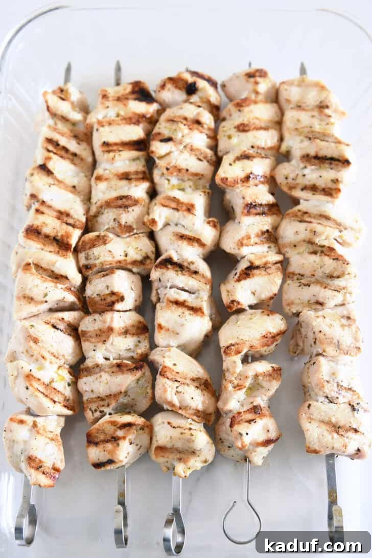 Succulent cooked chicken skewers, beautifully browned and caramelized from grilling, arranged in a glass 9x13-inch pan, showcasing their juicy and flavorful appeal.