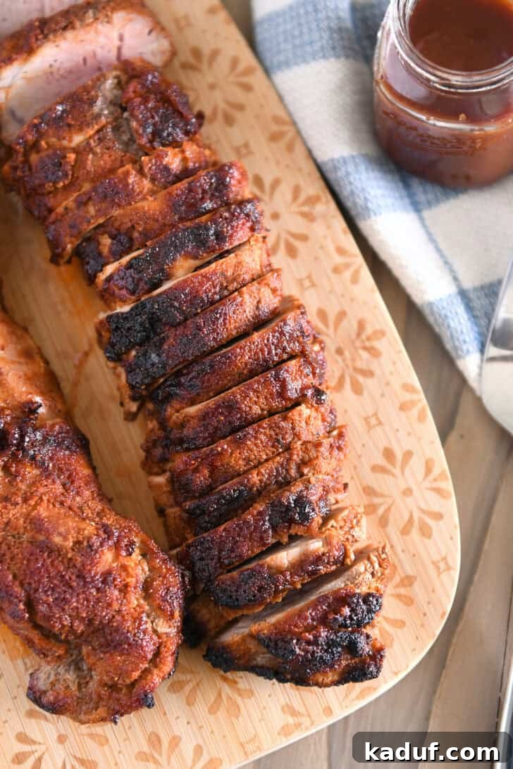 Quick and Tender Air Fryer Pork Tenderloin 7 A top-down view of perfectly sliced, juicy pork tenderloin fanned out on a rustic wood cutting board, showcasing its tender texture.