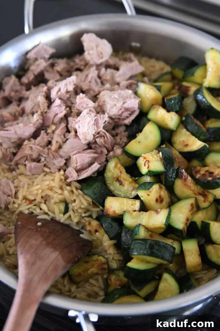 Effortless Tuna Zucchini Orzo Skillet 5 A stainless steel skillet filled with a harmonious blend of cooked orzo, flaky tuna, and tender zucchini, ready for the final touches.