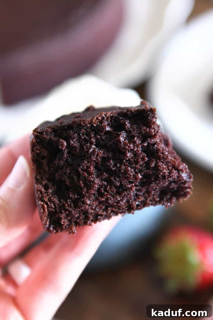 Velvety Chocolate Olive Oil Cake 12 Holding half piece of chocolate olive oil cake in fingers.