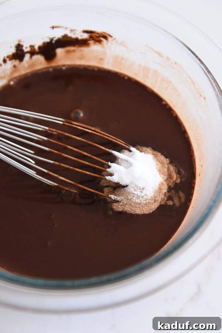 Velvety Chocolate Olive Oil Cake 5 Baking soda and salt added to cocoa powder and water in glass bowl with whisk.
