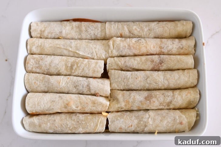 Savory Ground Beef Enchiladas 9 Ten rolled ground beef enchiladas in flour tortillas in white 9X13-inch dish.